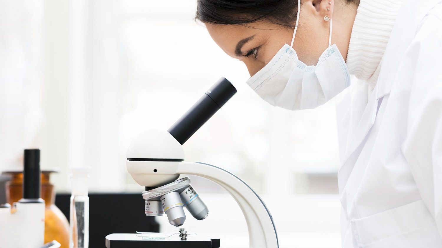 Profissional realizando análise em microscópio no Laboratório EXAME-PR